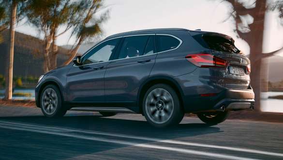 BMW X1 F48, vue de trois quarts arrière BMW X1 F48 LCI, vue de trois quarts arrière en mouvement devant un paysage montagneux.