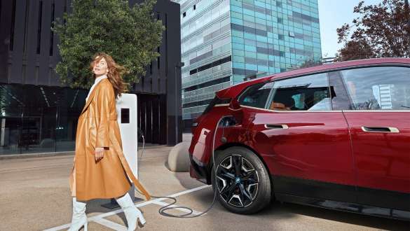 Solutions de recharge pour les employeurs – femme devant une BMW iX à une station de recharge
