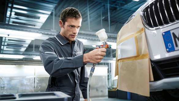 Un peintre-débosseleur repeint l’avant d’une BMW.