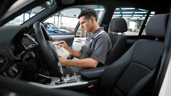 Assis à la place du passager, un employé du service BMW inspecte l’intérieur du véhicule.