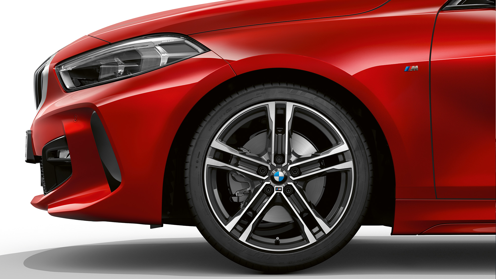 BMW Série 1, Modèle M Sport, vue de profil avant. BMW Série 1, Modèle M Sport en Melbourne Rot metallic, vue latérale avant, avec jantes BMW M 17" en alliage léger à doubles rayons 550 M, en exécution bicolore.