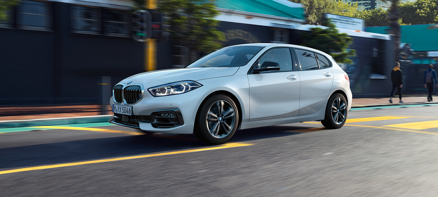 BMW Série 1, Modèle Sport, vue de trois quarts de profil. BMW Série 1, Modèle Sport en Mineralweiß metallic, vue de trois quarts de profil, en marche.