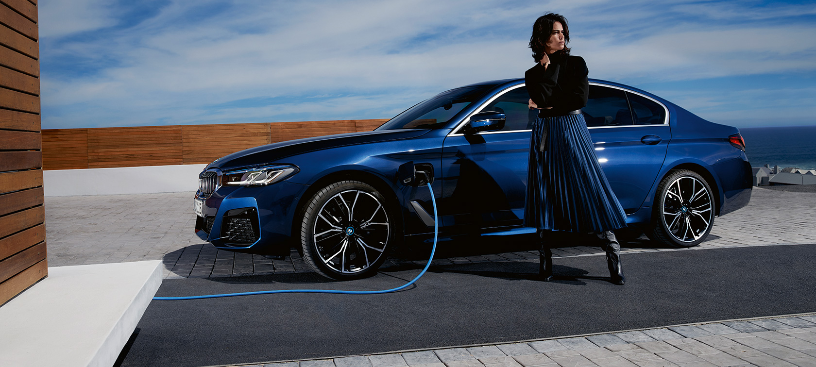BMW Série 5 Berline hybride rechargeable 2021 G30, vue de profil branchée à une borne de recharge BMW Série 5 Berline hybride rechargeable 2021 G30, vue de profil branchée à une borne de recharge avec modèle