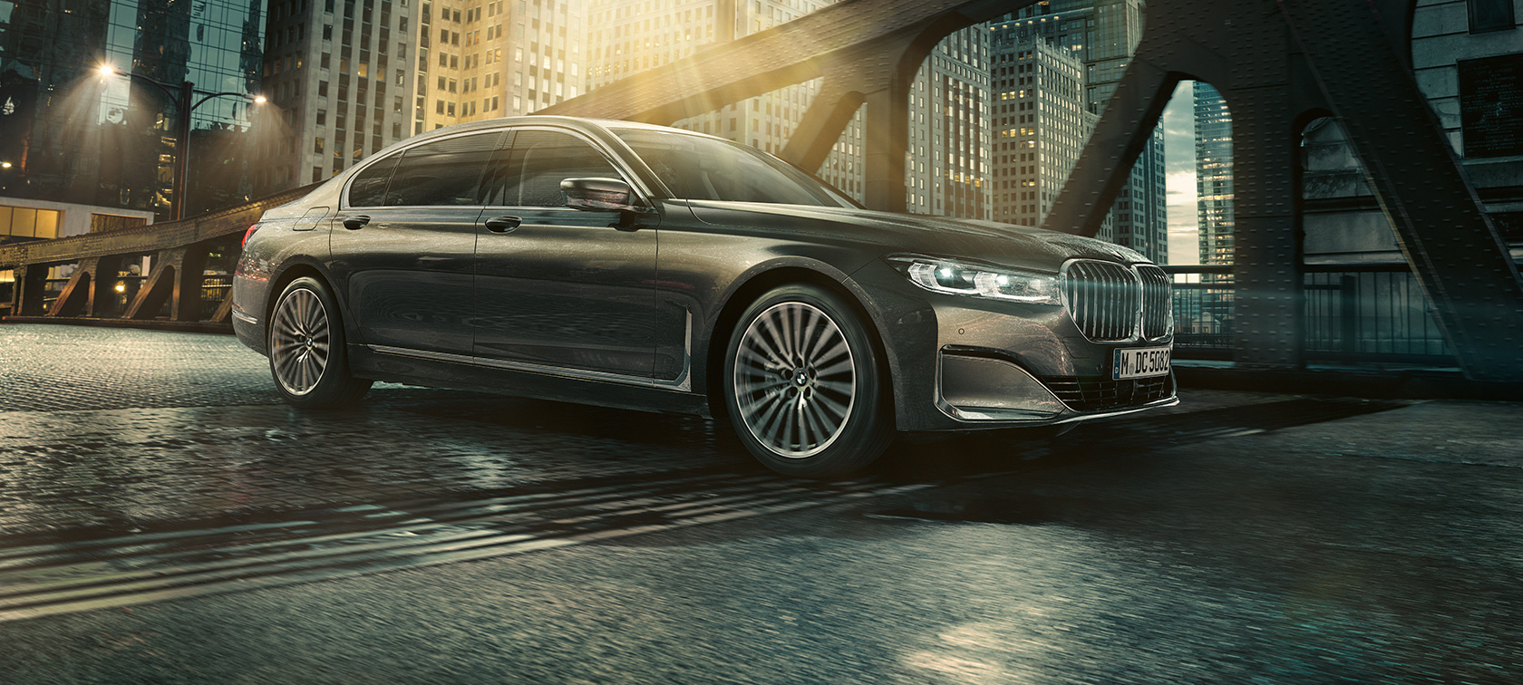 BMW Série 7 Berline, vue latérale Vue latérale de la BMW Série 7 Berline avec portière ouverte devant un hôtel éclairé.