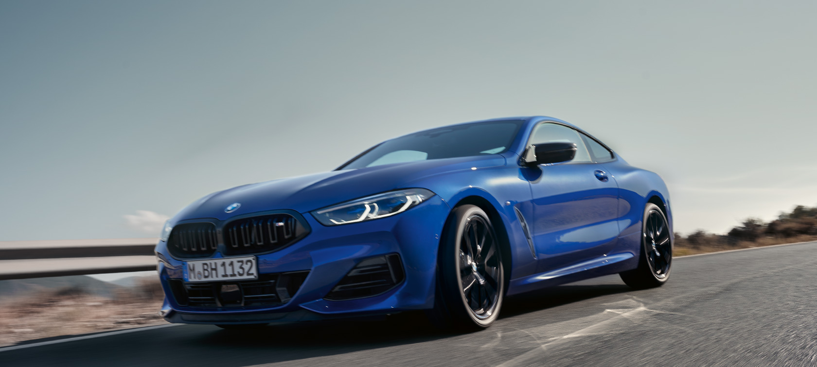La nouvelle BMW Série 8 Coupé G15 LCI restylage 2022 BMW M850i xDrive M Portimao Blau metallic, vue avant en contre plongée en mouvement La nouvelle BMW Série 8 Coupé G15 LCI restylage 2022 BMW M850i xDrive M Portimao Blau metallic vue de l'avant vue en contre plongée en mouvement sur une route de campagne devant un paysage vallonné