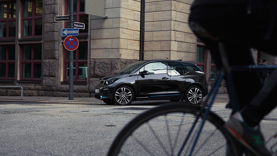 BMW i3s I01 2018 en Fluid Black avec accent BMW i Blau vue de profil en mouvement dans un décor urbain
