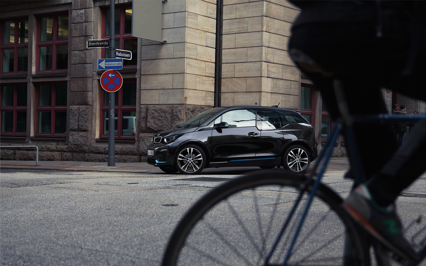 BMW i3s I01 2018 en Fluid Black avec accent BMW i Blau vue de profil en mouvement dans un décor urbain