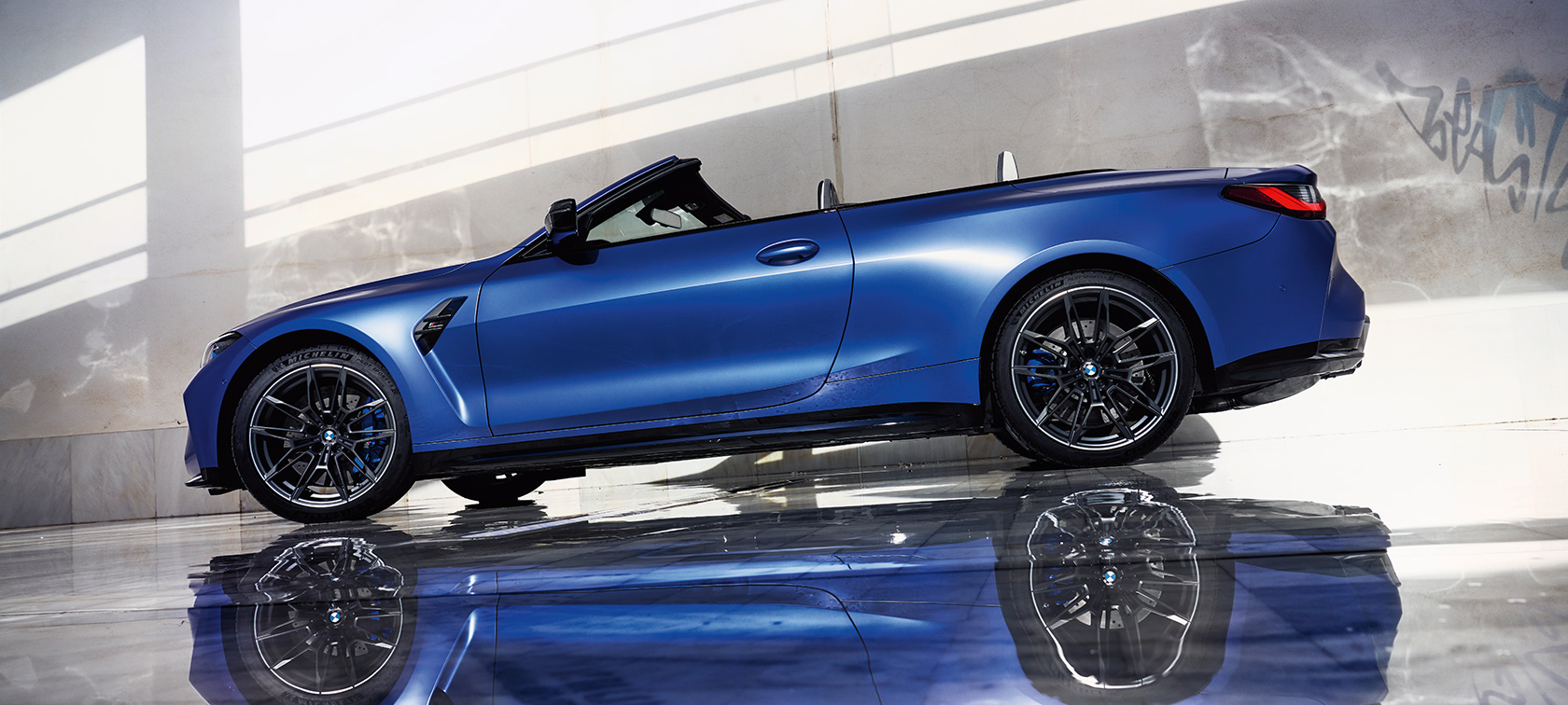 BMW M4 Competition Cabrio avec M xDrive G83 2021, vue de trois quarts avant en mouvement BMW M4 Competition Cabrio avec M xDrive G83 2021 BMW Individual Frozen Portimao Blau metallic, vue de trois quarts avant en mouvement
