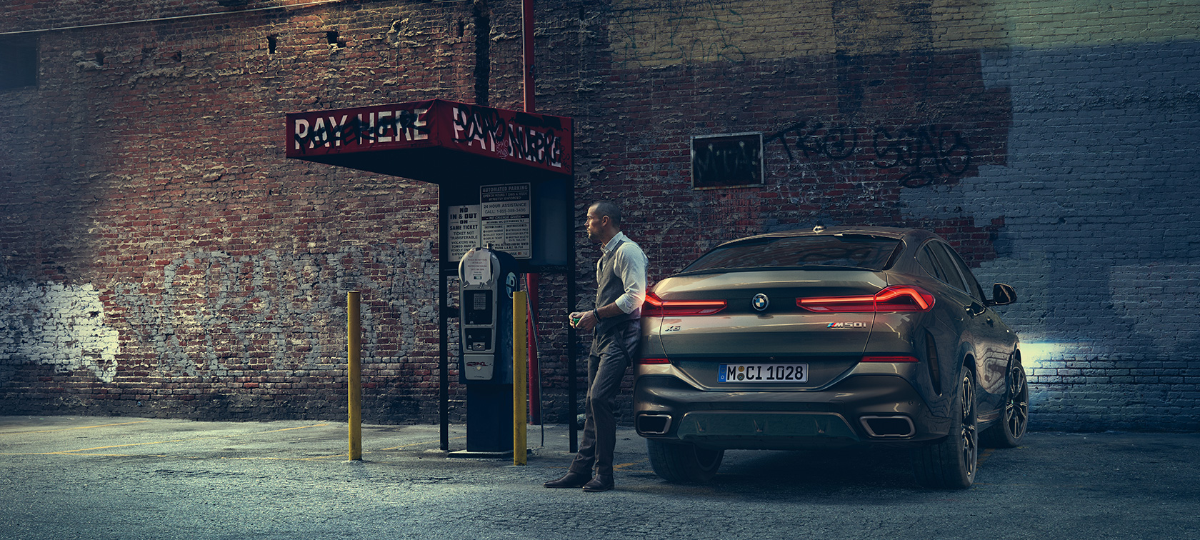 Arrière de la BMW X6 M50i. Homme en appui sur l’arrière de la BMW X6 M50i.