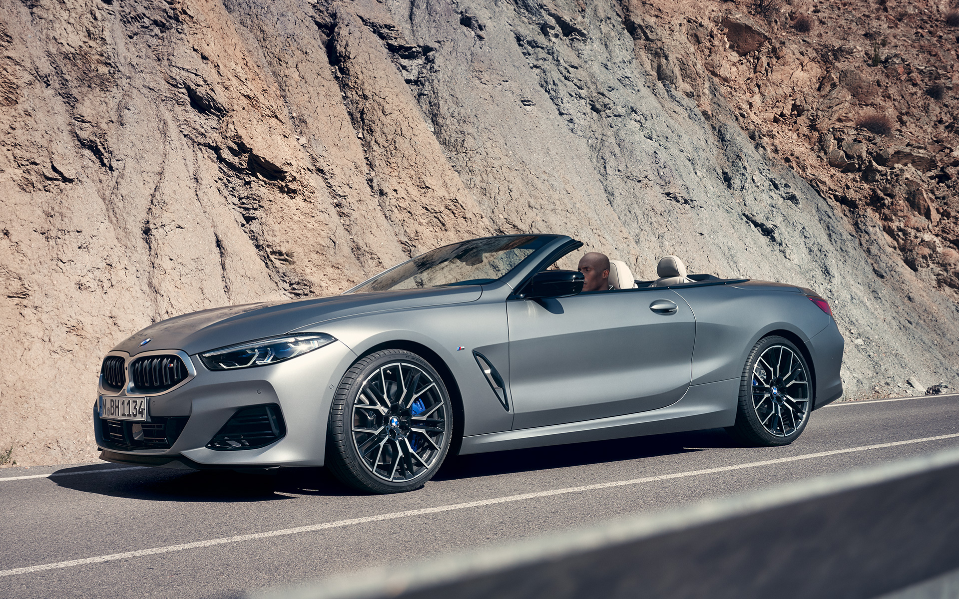 Vue de trois quarts avant la nouvelle BMW M850i xDrive Cabrio G14 LCI restylage 2022 La nouvelle BMW M850i xDrive Cabrio G14 LCI restylage 2022 BMW Individual Frozen Pure Grey metallic, vue de trois quarts avant en mouvement devant des roches