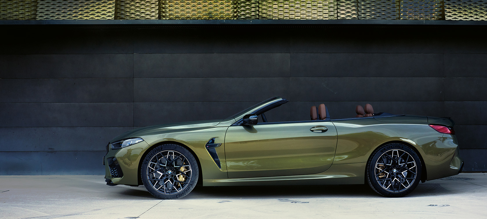 La nouvelle BMW M8 M Competition Cabrio F91 LCI restylage 2022 vue de profil en stationnement La nouvelle BMW M8 M Competition Cabrio F91 LCI restylage 2022 BMW Individual Brass metallic Vue de profil en stationnement avec portière ouverte et mannequin femme