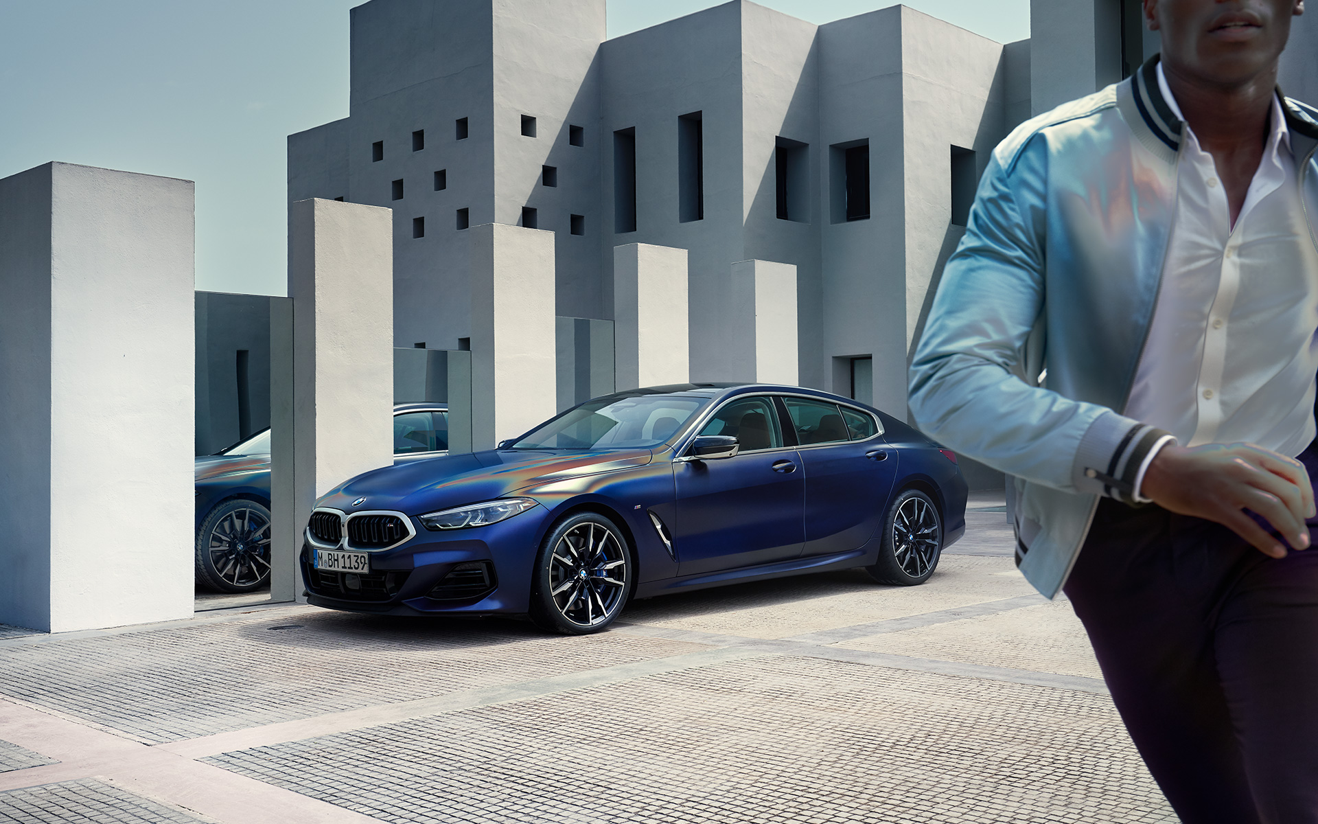 Vue de trois quarts avant BMW M850i xDrive Gran Coupé G16 LCI restylage 2022 BMW M850i xDrive Gran Coupé G16 LCI restylage 2022 BMW Individual Frozen Tansanitblau metallic vue de trois quarts avant à l’arrêt avec modèle masculin au premier plan
