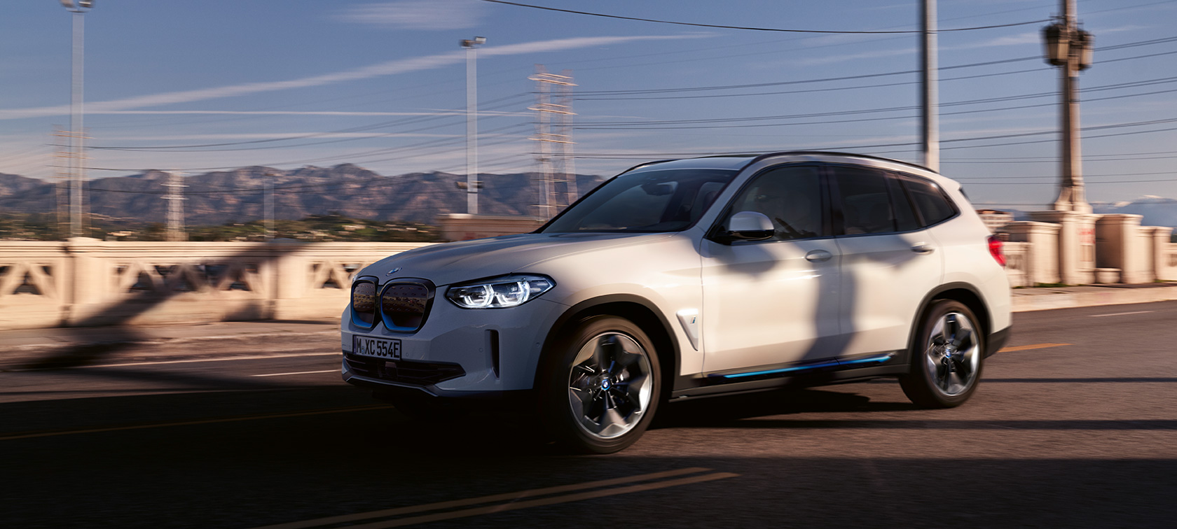 BMW iX3 G08, vue de trois quarts avant en mouvement sur la route BMW iX3 G08 2020 en Mineralweiß metallic, vue de trois quarts avant en mouvement sur la route