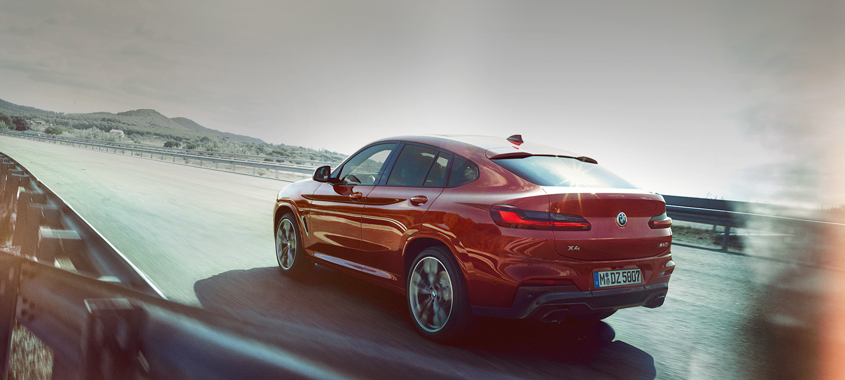 BMW X4 en mouvement sur la route BMW X4 M40i G02 2018 en Flamencorot Brillanteffekt Rot Vue de trois quarts arrière en mouvement sur la route