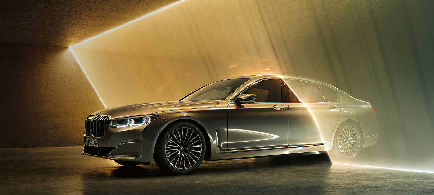 La BMW Série 7 Berline vue de trois quarts avant. BMW Série 7 Berline : vue de trois quarts avant d’une BMW grise entourée de rayons lumineux.