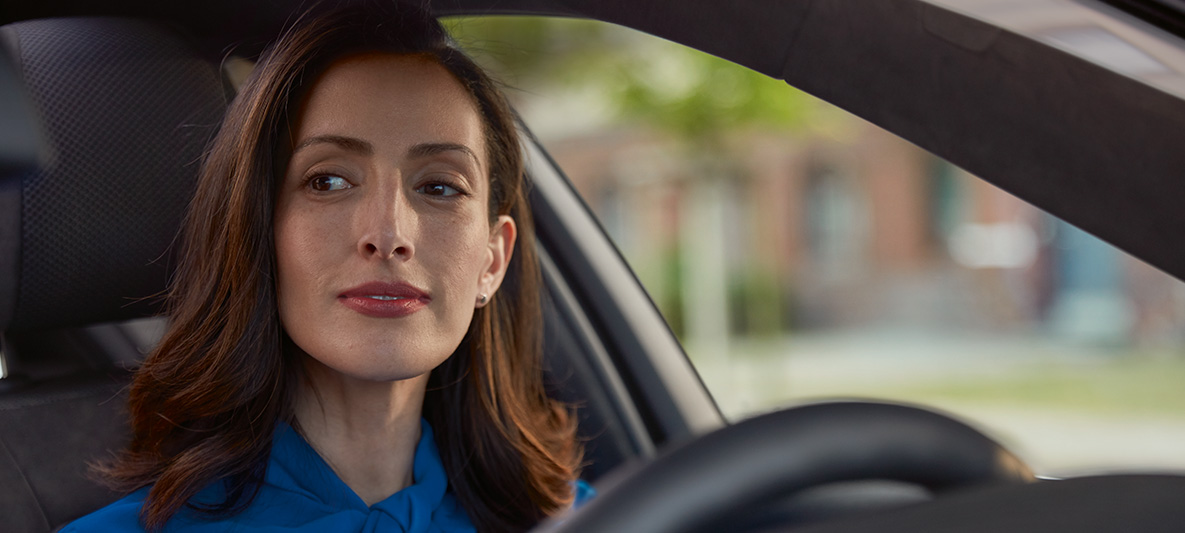Une femme tout sourire au volant de sa BMW.